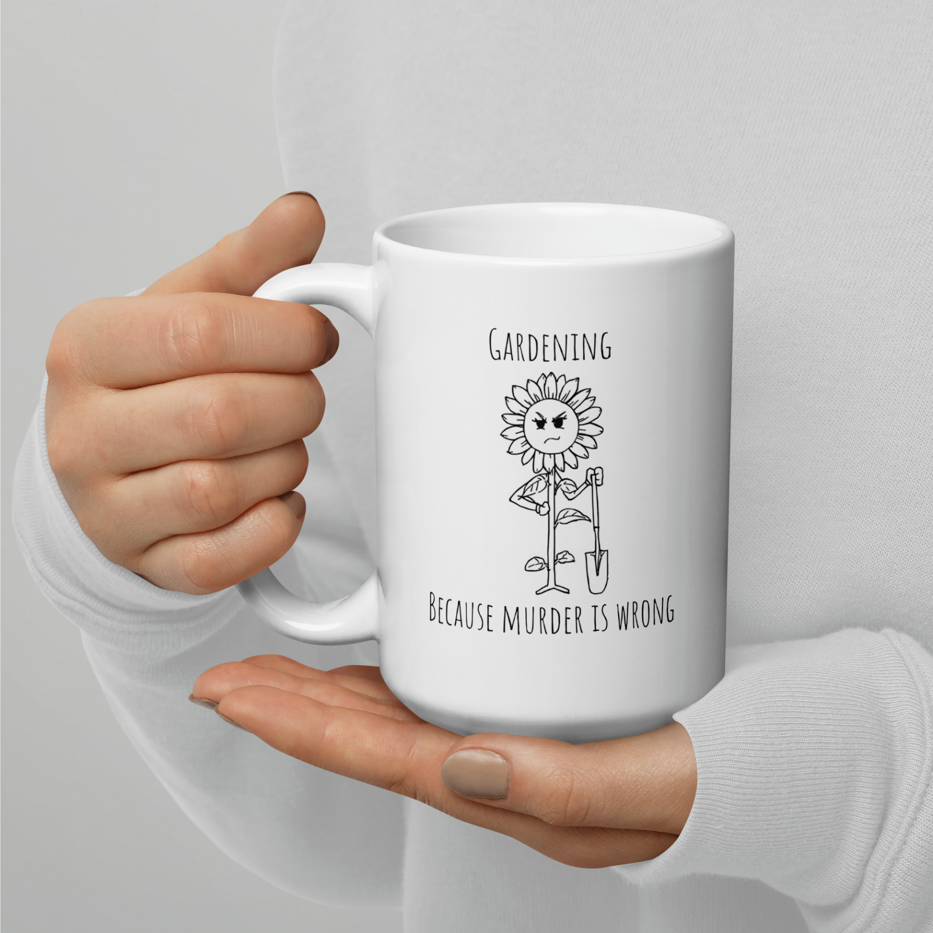 White glossy ceramic mug reading 'Gardening: Because murder is wrong' with an angry sunflower holding a shovel